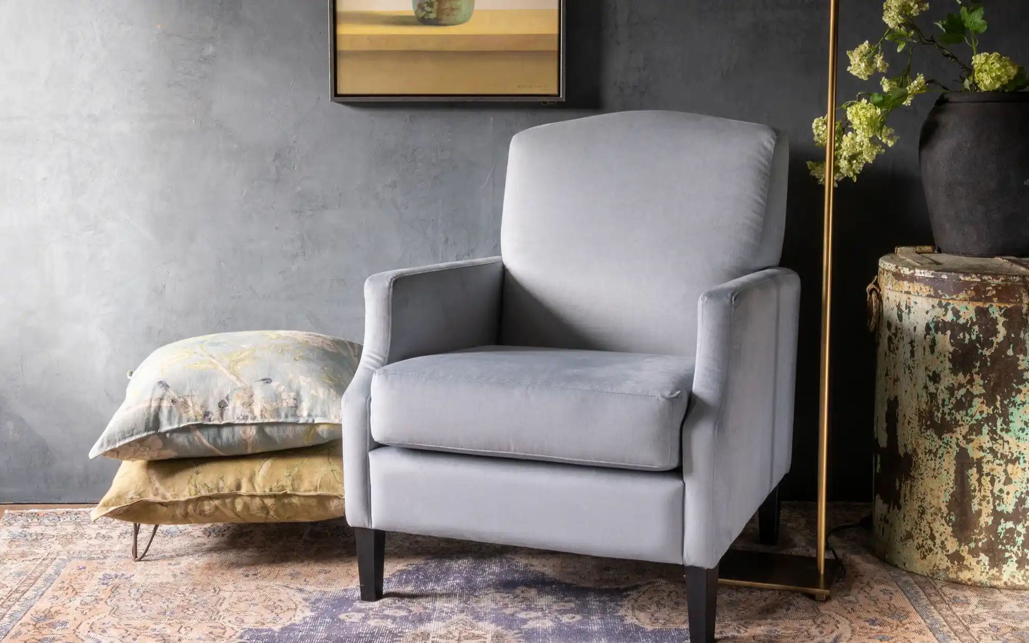 Klassieke fauteuil Quinn in landelijke woonkamer, sfeervol gepresenteerd tegen een grijze gekalkverfde muur.